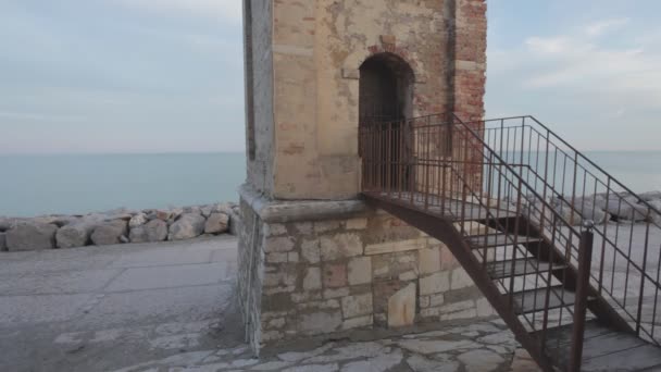 Donna vestita di nero entra in un campanile con il mare all'orizzonte — Video Stock