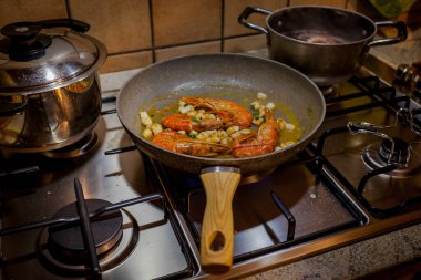 Tavada karides pişirip sobanın üstünde yatıyorsun.