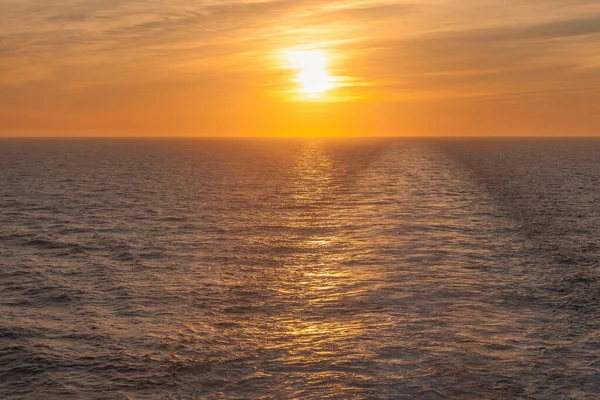 Puesta de sol en el mar donde se puede ver el velorio dejado por un crucero — Foto de Stock