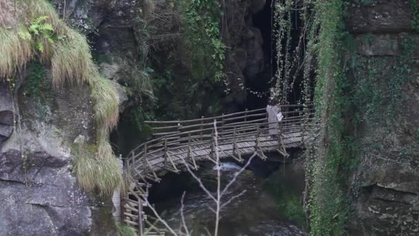 Mulher em uma ponte de madeira passando em um belo desfiladeiro — Vídeo de Stock