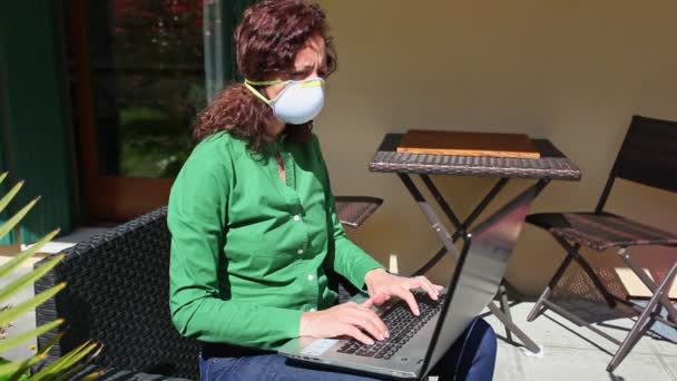 Nő ül a kertben, visel anti-covid maszk, használata közben a laptop — Stock videók
