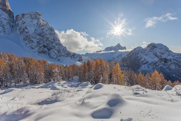 Winterpanorama aus orangefarbenem Lärchenwald mit der Sonne über dem Gipfel des Civetta — Stockfoto