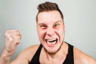 Arka planda bağıran sakallı ve yumruklu öfkeli genç adam..