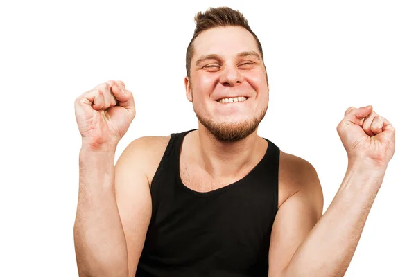 Junge lustige bärtige Kerl glückliche Gewinner gekleidet in schwarzen T-Shirt hebt die Hände mit den Fäusten nach oben isoliert auf weißem Hintergrund. — Stockfoto