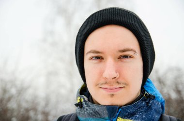 Arka planda bulanık duran şapkalı genç adamın portresini kapat.