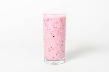 Bir bardak yoğurt kokteyli, meyve püresi, ahududulu beyaz arka planda izole edilmiş bir kütüğün üzerinde duruyor..