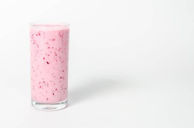 Bir bardak yoğurt kokteyli, meyve püresi, ahududulu beyaz arka planda izole edilmiş bir kütüğün üzerinde duruyor..