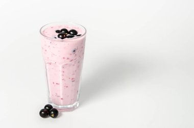 Bir bardak yoğurt kokteyli, üzümlü smoothie, beyaz arka planda bir huş ağacının üzerinde duruyor..