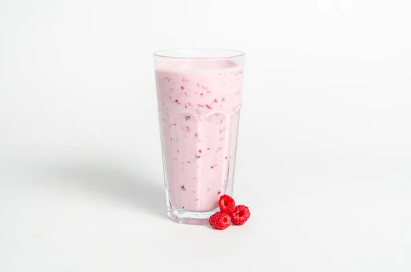 Verre de cocktail de yaourts, smoothies, avec des framboises se dresse sur une souche de bouleau, isolé sur fond blanc . — Photo