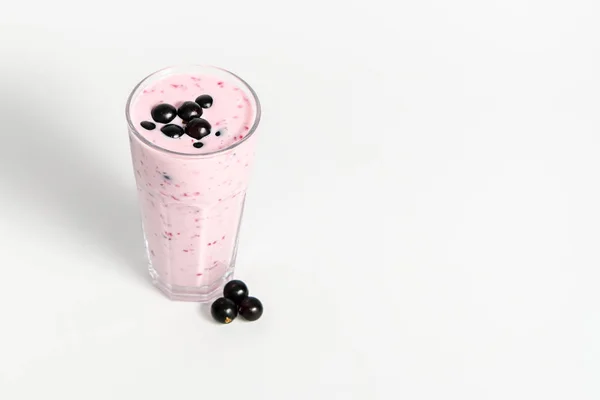 Verre de cocktail de yaourt, smoothies, avec baies de cassis, se tient sur une souche de bouleau sur fond blanc . — Photo