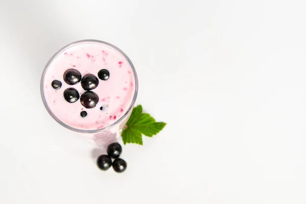 Verre de cocktail de yaourt, smoothies, avec baies de cassis, se tient sur une souche de bouleau sur fond blanc . — Photo