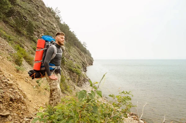Junger Mann Tourist mit Rucksack am See und in den Bergen — Stockfoto
