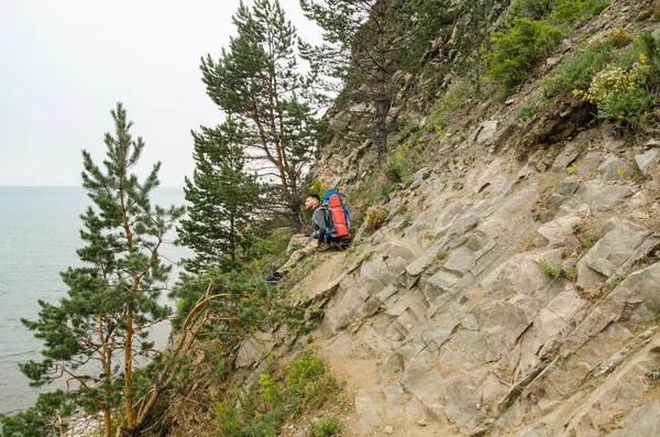 Молодой турист с рюкзаком на фоне озера и гор — стоковое фото