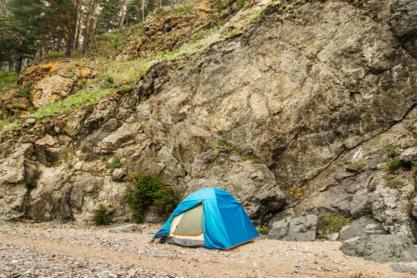 Uma tenda azul fica nas montanhas nas rochas junto ao lago — Fotografia de Stock