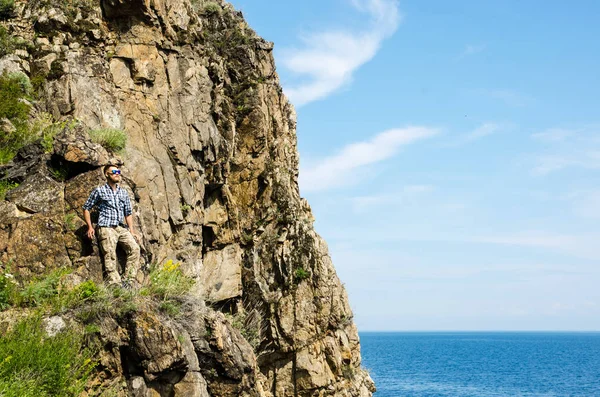 Young guy tourist travels on the background of rocks in a shirt and sunglasses — Stock Photo, Image