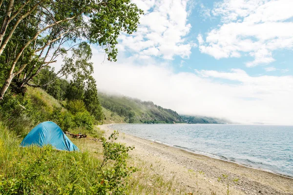 Niebieski namiot stoi w górach na skałach nad jeziorem. — Zdjęcie stockowe