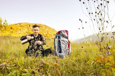 En yüksek dağında gün batımı zevk sırt çantası ile yenilikçi genç adam.