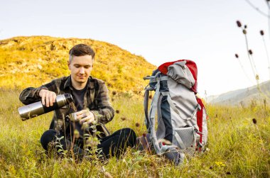 En yüksek dağında gün batımı zevk sırt çantası ile yenilikçi genç adam.