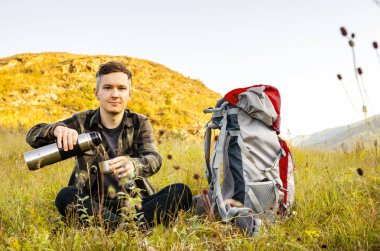 En yüksek dağında gün batımı zevk sırt çantası ile yenilikçi genç adam.