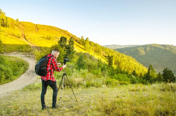 사진 작가는 카메라를 들고 자연 속의 바위 위에 서 있습니다. 여행 개념. — 스톡 사진