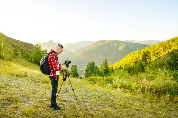사진 작가는 카메라를 들고 자연 속의 바위 위에 서 있습니다. 여행 개념. — 스톡 사진