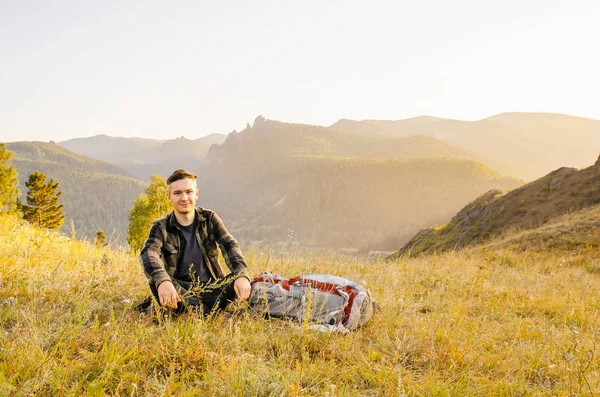 Hipster giovane uomo con zaino godendo il tramonto sulla montagna di picco . — Foto Stock