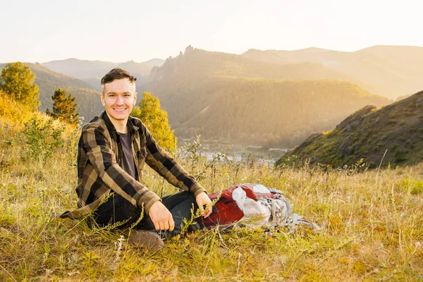 Hipster joven con mochila disfrutando de la puesta del sol en la montaña pico . — Foto de Stock