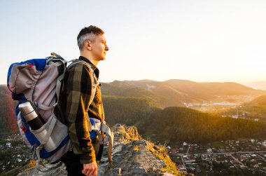 En yüksek dağında gün batımı zevk sırt çantası ile yenilikçi genç adam.