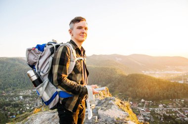 En yüksek dağında gün batımı zevk sırt çantası ile yenilikçi genç adam.