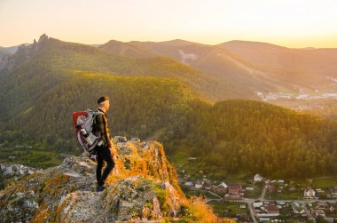 En yüksek dağında gün batımı zevk sırt çantası ile yenilikçi genç adam.