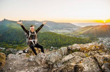 En yüksek dağında gün batımı zevk sırt çantası ile yenilikçi genç adam.