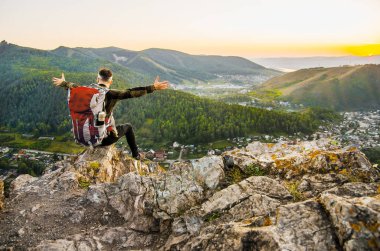 En yüksek dağında gün batımı zevk sırt çantası ile yenilikçi genç adam.