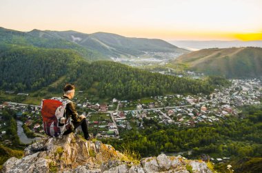En yüksek dağında gün batımı zevk sırt çantası ile yenilikçi genç adam.