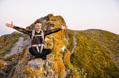 En yüksek dağında gün batımı zevk sırt çantası ile yenilikçi genç adam.