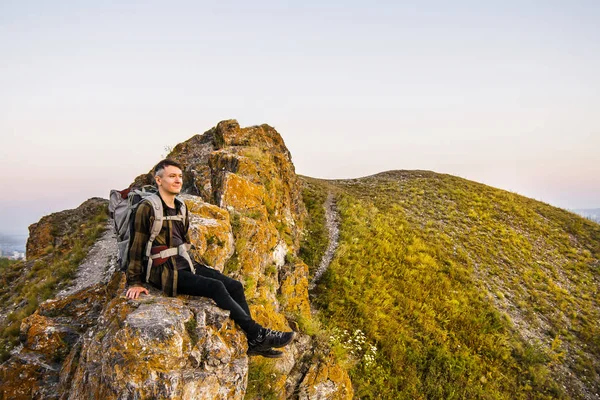 피크 산에 일몰을 즐기는 배낭 hipster 젊은 남자. — 스톡 사진