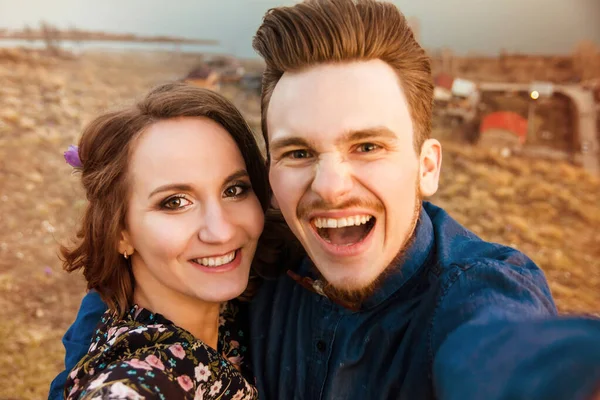 Par i kärlek glada promenader och omfamna på floden bakgrund — Stockfoto