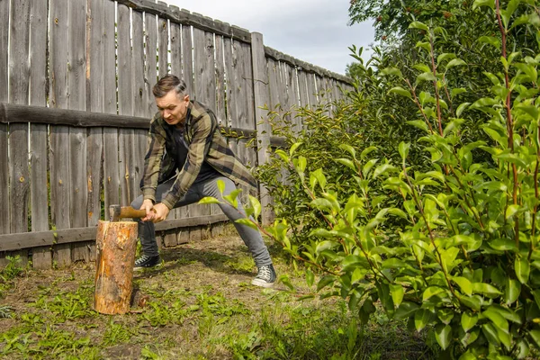 Holzfäller hacken Holz. Junger Mann hackt mit Axt Holz — Stockfoto