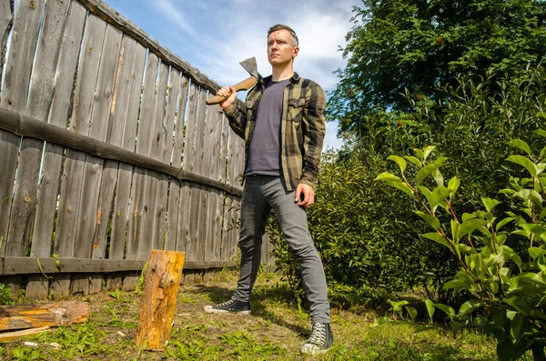 Holzfäller hacken Holz. Junger Mann hackt mit Axt Holz — Stockfoto