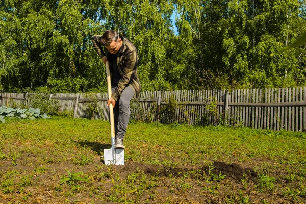 Jovem cavou o chão no jardim com uma pá — Fotografia de Stock