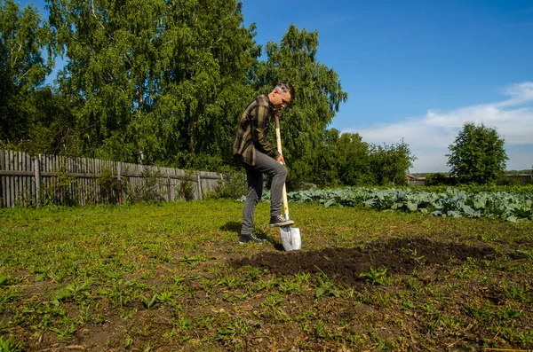 Junger Mann gräbt mit Schaufel den Boden im Garten um — Stockfoto
