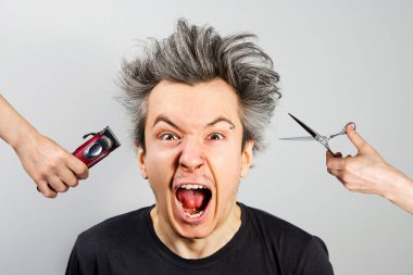 Kırpıcı ile el ve makasla el, beyaz arka planda sakallı, aşırı büyümüş, tıraşsız bir adam.