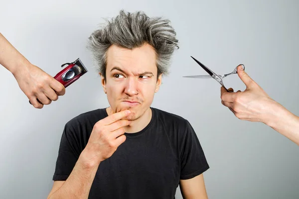 Hand with clipper and hand with scissors cut overgrown unshaven guy with a beard on a white background — Stock Photo, Image