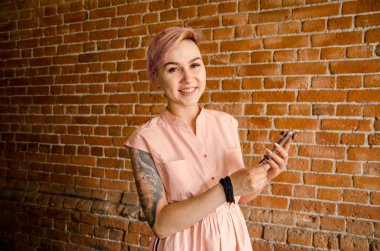 Genç ve güzel bir kız, duvarın arkasında cep telefonuyla konuşuyor.