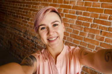 Tuğla duvardaki güzel kız selfie çekiyor.