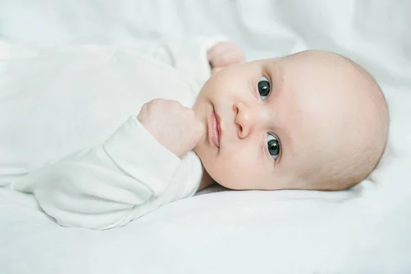 Close up portrait of baby boy lying on white linen — 스톡 사진