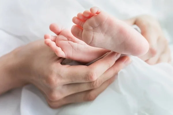 Os pés da criança nas mãos da mãe, de perto — Fotografia de Stock