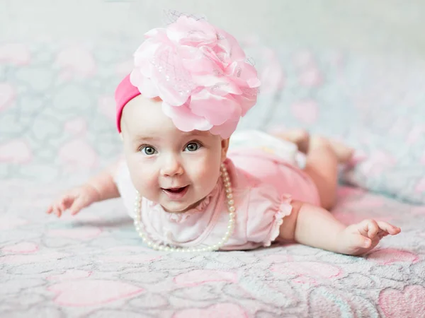 Açık pembe arka planda pembe elbiseli küçük bir kızın portresi..
