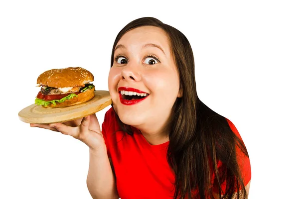 Mulher gorda jovem segura hambúrguer, sorri com a boca aberta isolada no fundo branco . — Fotografia de Stock