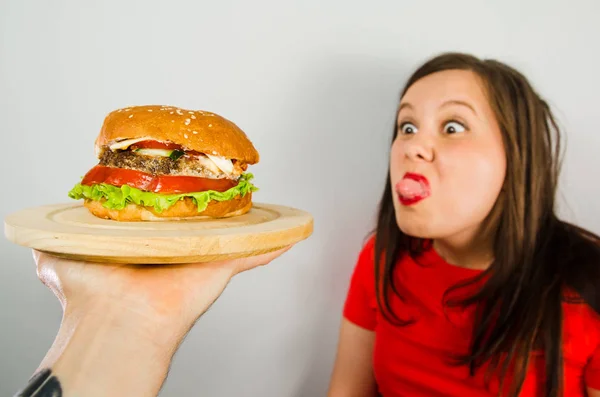 Ung flicka vägrar fett ohälsosam hamburgare eftersom hon går ner i vikt och bantning på grå bakgrund. — Stockfoto