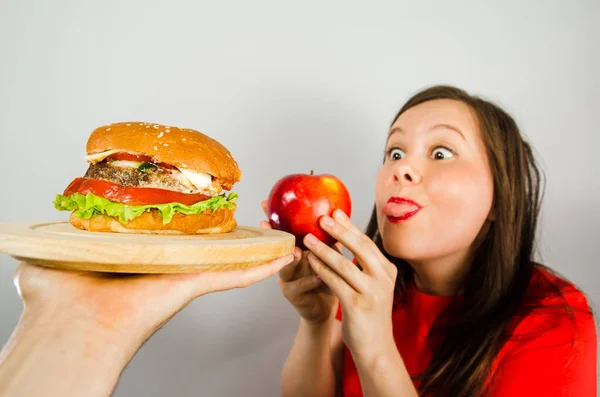 Young girl refuses fat unhealthy hamburger because she is losing weight and dieting on gray background. — 스톡 사진